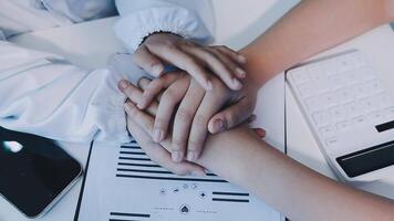 Two people holding hands over a desk with a calculator video