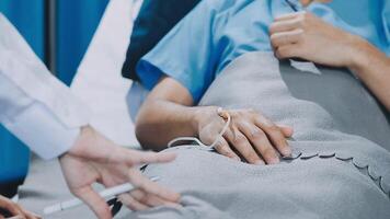 A doctor is holding a patient's hand while they are laying on a bed video