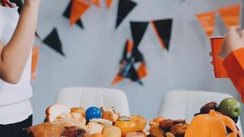 A woman is holding a cup of orange juice while standing next to a table with a pumpkin, video