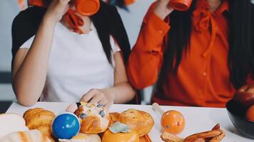 Two women drinking from cups while sitting at a table with food video
