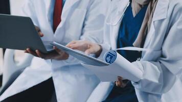 Two doctors are sitting in a chair with a laptop video