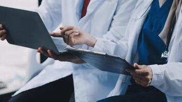 Two doctors are sitting on a bus and using a laptop video