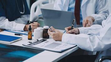Three doctors sitting at a table with a laptop video