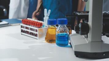 A group of people in lab coats standing around a microscope video