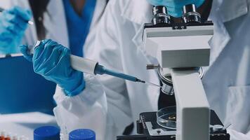 Two people in lab coats and gloves are working on a microscope video