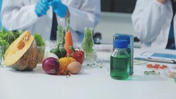 Two people in lab coats are working on a table with vegetables and other food video