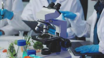 A group of people in lab coats are working on a microscope video
