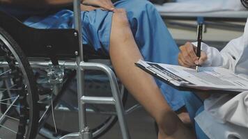 A doctor is writing on a clipboard while a patient sits in a wheelchair video