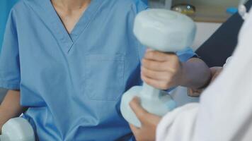 A doctor is holding a dumbbell in front of a patient video
