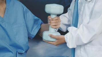 A doctor is holding a dumbbell while a patient is sitting in a bed video