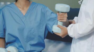 A woman in scrubs is holding a dumbbell video