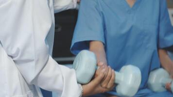A doctor is holding a dumbbell while a woman is sitting on a chair video