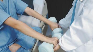 A doctor is holding a dumbbell in front of a patient video