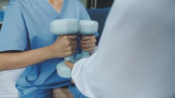 A nurse is holding two dumbbells while sitting on a bed video