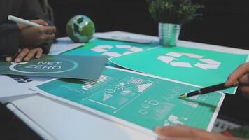 A group of people sitting at a table with green paper video