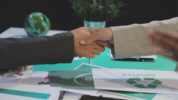 Two business people shaking hands over a table with recycling signs video