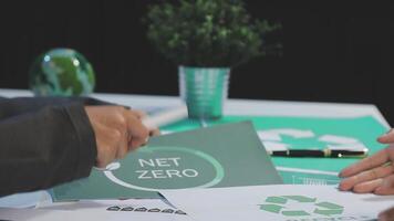 Two people sitting at a table with a net zero logo video