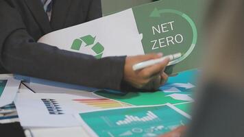 A man in a suit holding a net zero sign video