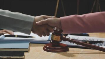 Two business people shaking hands over a table with a gavel video