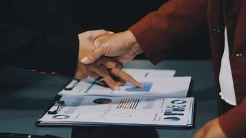 Two business people shaking hands over a table with papers video