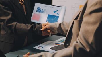 Two business people shaking hands over a table with graphs and papers video