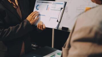 Two business people are holding a clipboard and looking at a chart video