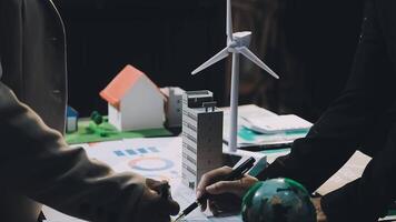 Two people are standing over a table with a wind turbine video