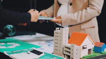 A man and woman are holding a paper with a model house on it video