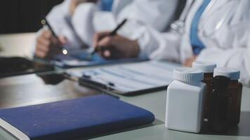 Two doctors are sitting at a table with a notebook and bottles video