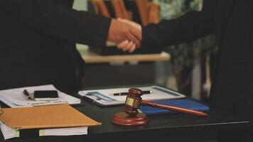 Two business people shaking hands over a desk with a gavel video
