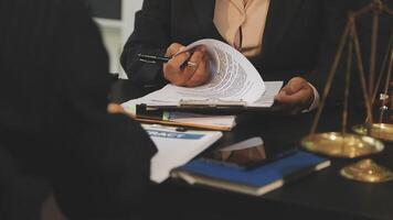 A man and woman are sitting at a desk with papers and a scale video