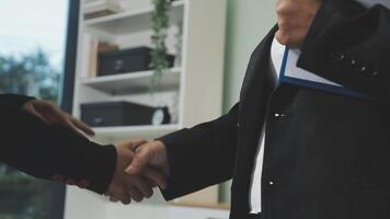 Two business people shaking hands in an office video