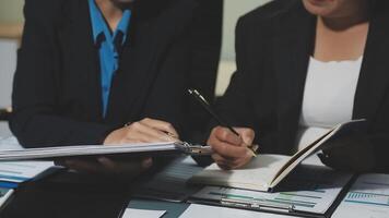 Two business people sitting at a table with papers and pens video