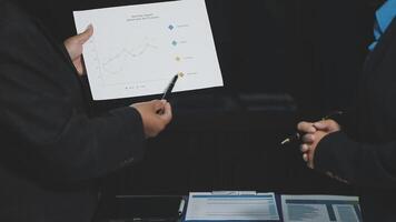 Two business people are holding a paper with graphs on it video