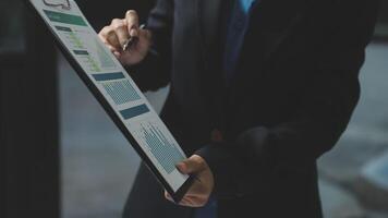 A person in a suit holding a clipboard with graphs and charts video