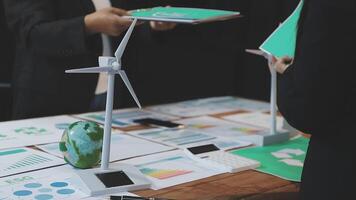 Business people standing around a table with papers and wind turbines video