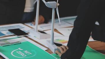 Business people working on a table with papers and wind turbines video