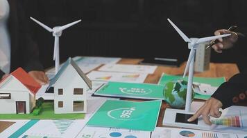 A group of people working on a paper model of a house with wind turbines video