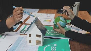 Business people working on a project with a house and a globe video