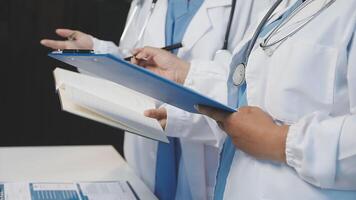 Two doctors are holding a clipboard and writing on it video