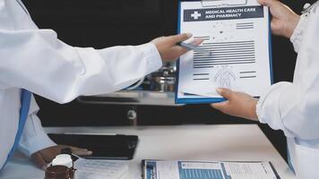 Two doctors are holding a clipboard and looking at a paper video
