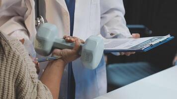 A doctor is holding a dumbbell while a woman is looking at it video