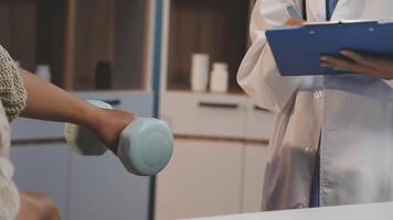 A doctor is holding a dumbbell in front of a patient video