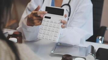A doctor is holding a calculator while looking at a patient video