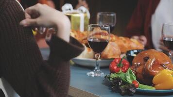 A woman is holding a glass of wine while sitting at a table with a turkey and vegetables video