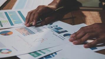 Businessman using pen to write on paper with graphs video