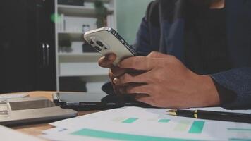 A man in a suit is using his phone while sitting at a desk video