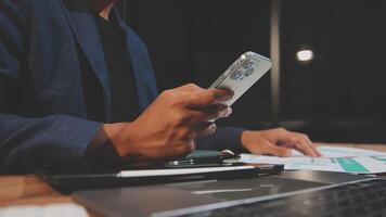 A man in a suit holding a cell phone while sitting at a desk video