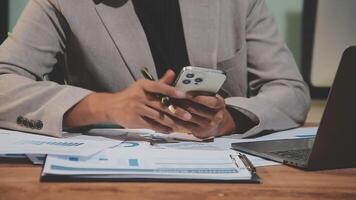 A man in a suit is using his phone while sitting at a desk video