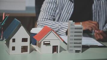A person is sitting at a desk with a house model video